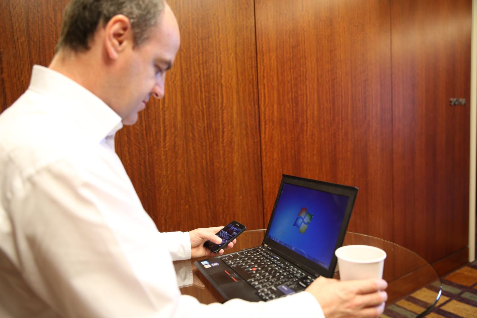 Man logging in on a laptop while holding a smartphone