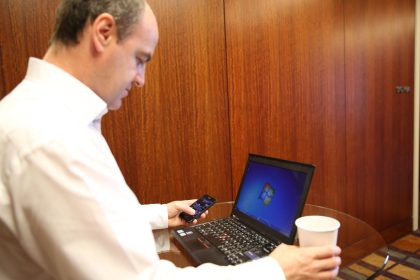Man logging in on a laptop while holding a smartphone